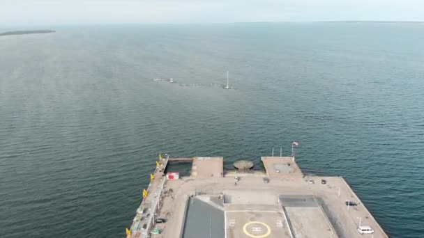 Aerial view of large gray pier with helicopter pad and walking people against blue cloudy sky and sea water in early spring. Stock. Marine landscape — Stock Video