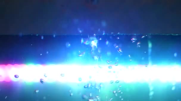 Vue latérale de beau mouvement chaotique de bulles d'oxygène, fond d'eau. Cadre. Réservoir en verre vide avec de l'eau et une lampe bleu vif sur le fond . — Video