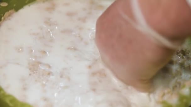 Close-up voor een hand in het koken van transparante handschoen mengen bakken ingrediënten in melk, voedselproductie concept. Stock footage. Bereiding van vloeibaar gebak in plastic kom. — Stockvideo