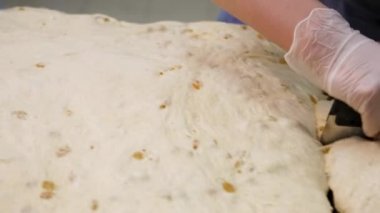 Pişirme eldivenleri özel bir bıçakla hamur parçalara kesme kadın için kapatın. Stok görüntüleri. Kadınlar elleri tahta tahta üzerinde parçalar halinde ham yoğuran hamur kesti.