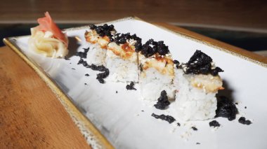 Close-up view of 4 delicious European rolls with eel, wasabi and ginger laying on a white rotating plate. Frame. Japanese food