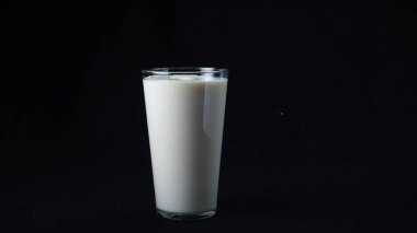 Slow motion of delicious milkshake with ice cream filling the clear glass on the black background. Frame. Cocktails with milk and ice cream
