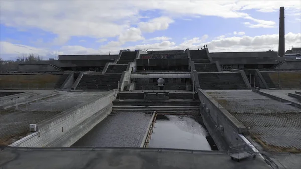 Zbliżenie lądowiska w pobliżu dużego, szarego kompleksu architektonicznego i dwóch schodów na tle niebieskiego zachmurzonego nieba wczesną wiosną. Akcje. Architektura miejska — Zdjęcie stockowe