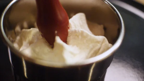 Κοντινό κομμάτι του λευκού γλυκού κρέμα συμπιέζεται σε ένα μικρό κύπελλο χάλυβα σε μια κουζίνα. Πλαίσιο. Επιδόρπια προετοιμασία — Φωτογραφία Αρχείου