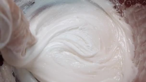 Primer plano de la mano de los panaderos en guantes de silicona mezclando crema de huevo blanco para pastelería en un tazón grande. Imágenes de archivo. Hornear pasteles — Vídeos de Stock