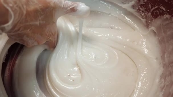 Primer plano de la mano de los panaderos en guantes de silicona mezclando crema de huevo blanco para pastelería en un tazón grande. Imágenes de archivo. Hornear pasteles — Vídeos de Stock