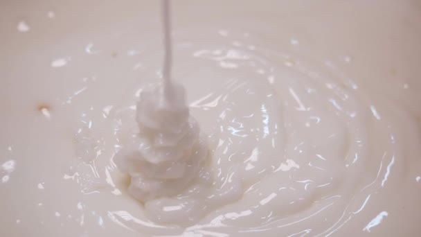 Close-up van wit ei crème voor gebak stroomt in een kom op een keuken of bakkerij. Stock footage. Taart bakken — Stockvideo