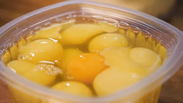 Закрыть яичные желтки в пластиковой таре, приготовить. Запись. Сырые свежие яйца, готовые к приготовлению на кухне . — стоковое фото