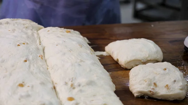 Närbild för Baker skära degen i bitar innan tillagning och vägning dem på bageriet. Stock film. Kvinna som gör brödbitar från rå bakverk en sätta in på skalan. — Stockfoto