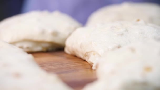 Nahsicht für rohe Gebäckstücke, die auf dem Holzbrett auf dem Tisch liegen. Archivmaterial. traditionelle leckere Gebäckstücke mit Rosinen bereit zum Backen. — Stockvideo