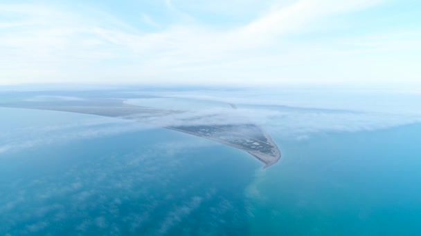 Blick von oben auf die Küste inmitten des Meeres am Horizont. Schuss. die höchste Aussicht am Himmel zwischen Wolken auf blauem Meer und dreieckigem Ufer — Stockvideo