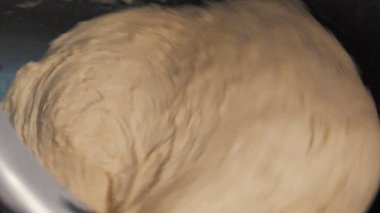 Close-up of mixing a dough for bread baking or other baked goods in a professional kneader machine in kitchen of bakery or at the manufacturing. Stock footage. Dough making process