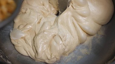 Close-up of raisin adding to dough in a professional kneader machine in kitchen of bakery or at the manufacturing. Stock footage. Dough making process