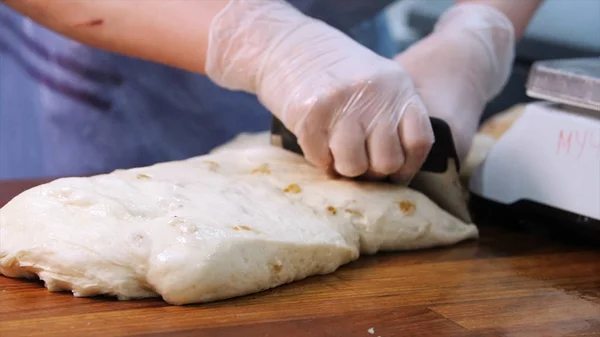 Крупный план рук пекаря в перчатках с использованием кухонной утвари и нарезанием теста на кухне в пекарне. Запись. Подготовка выпечки — стоковое фото