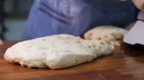 El primer plano de las manos del panadero en guantes usando utensilio de cocina y cortar una masa en la cocina en la panadería. Imágenes de archivo. Productos horneados preparación — Foto de Stock