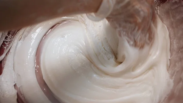 Close-up da mão do padeiro em luvas de silicone misturando creme de ovo branco para pastelaria em uma tigela grande. Imagens de stock. Cozimento de bolo — Fotografia de Stock
