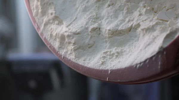 Close-up voor witte bloem wordt gezet in de ijzeren kom in de bakkerij, broodproducten concept. Stock footage. Witte bloem die uit de plastic kom valt. — Stockfoto