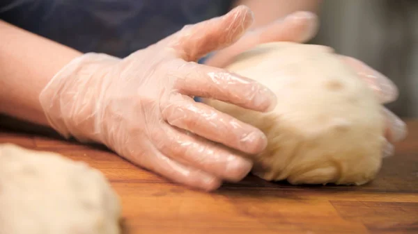Nő főzőkesztyű gyúrás tészta fa fórumon, élelmiszer-előkészítő koncepció. Készletfelvétel. Közel a kezét, hogy süteményt kenyérsütéshez. — Stock Fotó