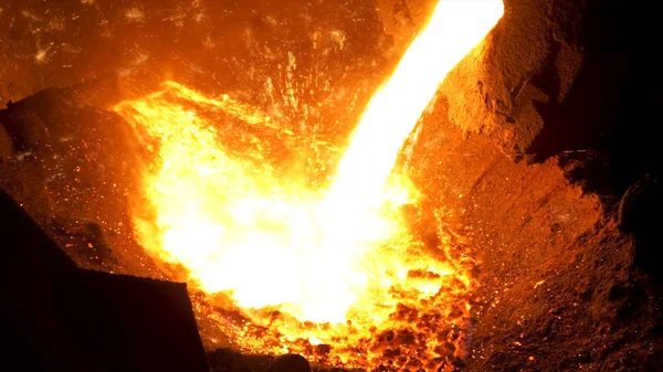 Smelting of the metal in the foundry at the steel mill. Stock footage. Close up for hot steel being poured from the furnace with many sparcles, iron industry.