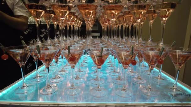 Many glasses for Martini with alcohol are on table in bar. Action. Mountains of wine glasses Martini with alcoholic drinks and cherries prepared for event barmen show — Stock Video