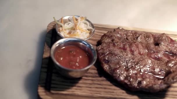 Gebakken stuk vlees geserveerd op houten dienblad. Actie. Close-up van sappige stuk steak gekookt door professionele chef-kok en geserveerd op de lade op een geïsoleerde achtergrond — Stockvideo