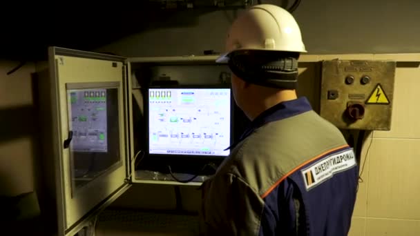 Dělník v hemletu a ochranný uniformě, kontroluje data na průmyslovém počítači, metalurgický koncept. Záběry ze skladu. Zadní pohled na inženýra při práci v továrně. — Stock video
