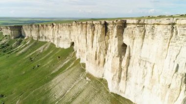 Ayak parlak yeşil çayır ile Kırım 'da beyaz kaya çarpıcı manzara. Atış. Bulutlu gökyüzü arka planda düz üst ve yeşil alan ile güzel dağ için hava.