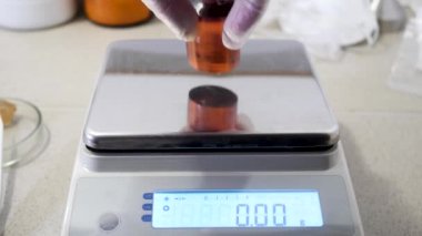 Jeolojik laboratuar detayları, mineraller tartım süreci, bilim kavramı. Stok görüntüleri. Tartıya kırmızı taş koyarak elinizin yakın görünümü.
