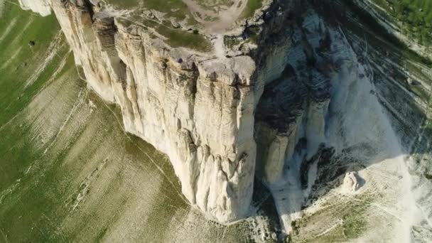 A view over white mountain cliffs, with hills and valleys, with green meadows on blue sky background. Shot. Aerial for the beautiful rock with steep slope, natural landscape. — Stock Video