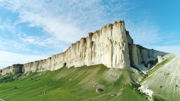 Pintoresca pendiente de acantilado blanco, piedras y colinas cerca de la hermosa pradera verde contra el cielo azul nublado en el día de verano. Le dispararon. Paisaje verano — Vídeo de stock