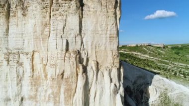 Mavi bulutlu gökyüzüne karşı sıcak yaz gününde arka planda güzel yeşil çayır ile kabartma beyaz uçurum eğim yakın bakış. Atış. Pitoresk yaz manzara