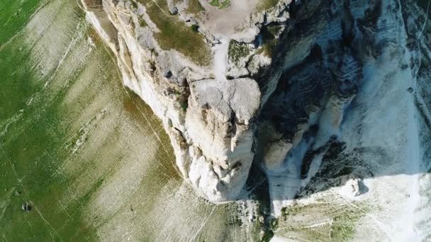 Εναέρια θέα του λευκού βράχου που καλύπτεται με πράσινο γρασίδι, λευκά μονοπάτια και λόφους πάνω από το λιβάδι την ηλιόλουστη μέρα του καλοκαιριού. Πυροβολισμό. Θέα από πάνω — Αρχείο Βίντεο
