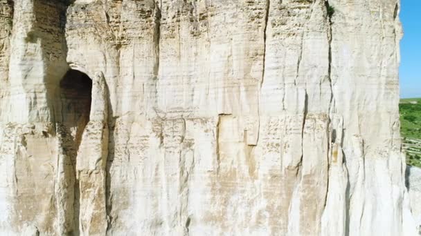 Vista de cerca de la pendiente del acantilado blanco en relieve con un gran agujero o gruta en medio de la pendiente. Le dispararon. Misteriosa cueva en el acantilado — Vídeos de Stock