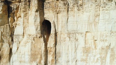 Eğim ortasında büyük delik veya mağara ile kabartma beyaz uçurum eğim yakın bakış. Atış. Uçurumda gizemli mağara