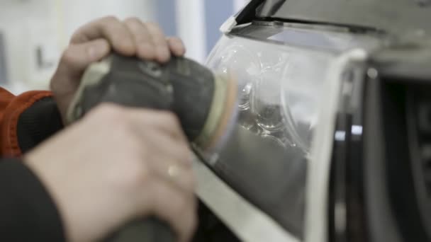 Κοντινό για auto μηχανικός μπούβισμα και Γυάλισμα κεφαλής αυτοκινήτου. Φως. Άρθρο. Εργαζόμενος στίλβωση του προβολέα ενός αυτοκινήτου στην επισκευή αυτοκινήτων και την ανανέωση του σταθμού σέρβις, χρησιμοποιώντας μια επαγγελματική μηχανή buffer — Αρχείο Βίντεο