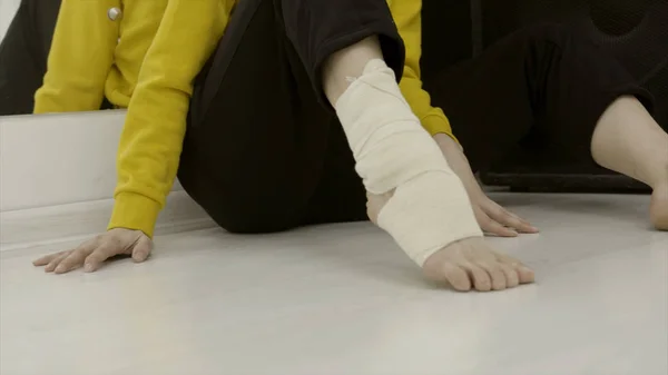 Close-up woman bandaging her leg with elastic bandage. Action. Unexpected injury or stretching of ankle while exercising and applying elastic bandage