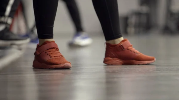 ,Close-up de pernas de mulheres ambulantes em tênis esportivos. Acção. Sapatilhas femininas elegantes para esportes ou fitness no ginásio — Fotografia de Stock