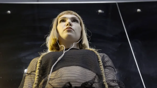 Young woman wearing small headphones. Action. Bottom view of young attractive woman epic wearing headphones with music before performance