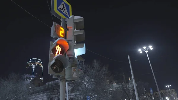 Un semáforo peatonal brillante. Acción. El semáforo peatonal cambia de rojo a verde indicando que puede cruzar la carretera. El semáforo brilla brillantemente contra el cielo nocturno de la ciudad — Foto de Stock