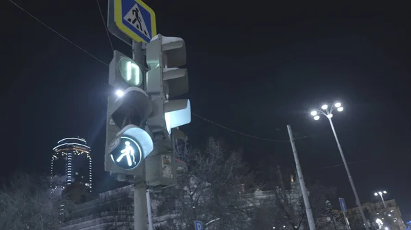 Світлове пішохідне світло. Дія. Пішохідні перемикачі світлофора від червоного до зеленого знака вказують на те, що ви можете перетинати дорогу. Світлофор яскраво сяє на нічне небо в місті — стокове фото