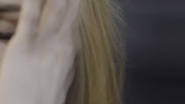 Junge Frau steckt Haare hinter Ohr. Aktion. Die attraktive junge Frau steckt ihre Haare mit einem Ohrstecker hinter das Ohr. moderne komfortable weiße Kopfhörer mit berührendem Klang — Stockvideo