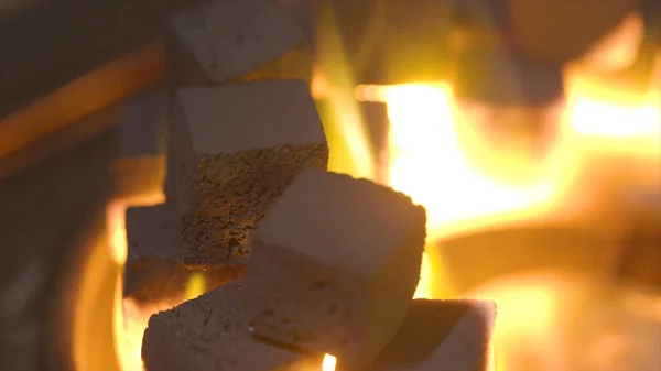 Close-up of burning charcoal cubes. Action. Cubes of embers burning in bowl for smoking hookah. Combustion of small flame of yellow fire burning pieces of coal