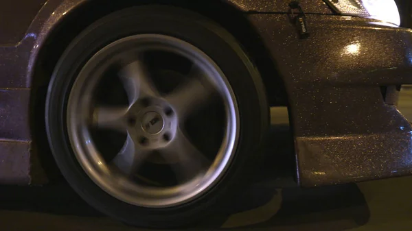 Gros plan de paillettes sur la voiture. L'action. Design moderne de revêtement de voiture avec paillettes d'or scintillant de la lumière des lanternes sur piste urbaine de nuit — Photo