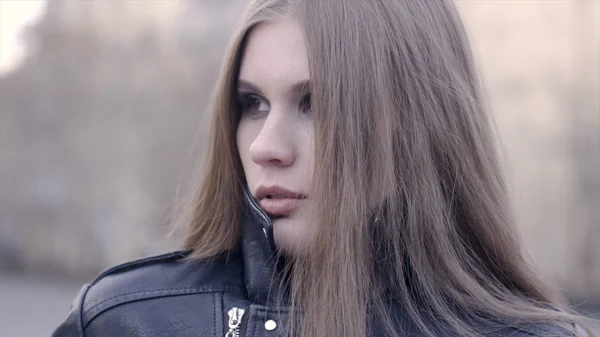 Stylish woman looking at camera outdoors in the street. Action. The face of a satisfied young woman in the city