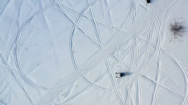 Vue du dessus des motoneiges. Des images. Vue de dessus de deux motoneiges circulant en cercle laissant des empreintes de pas dans la neige par temps ensoleillé — Photo