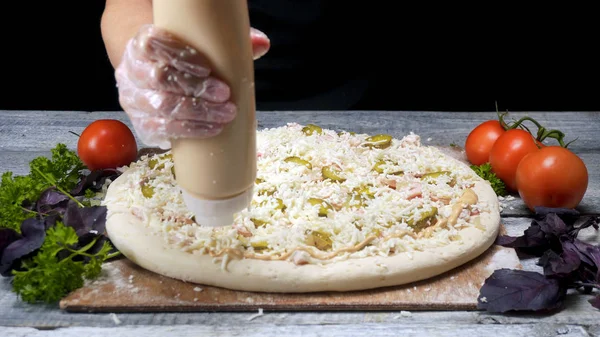 Chef watering pizza sauce. Frame. Professional chef in gloves for cooking trying to squeeze out of tube of pizza sauce surrounded by vegetables