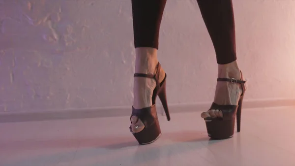 Primer plano para zapatos negros para pole dance con tacones altos en las piernas de una bailarina, concepto de danza moderna. Acción. Una mujer que se mueve en tacones altos en el estudio pole contra la pared . —  Fotos de Stock