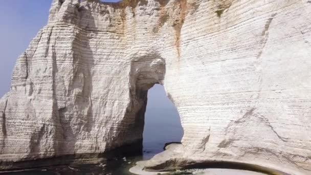 Aéreo para o belo arco em rocha branca acima do mar calmo em um dia ensolarado de verão, formas e formas da natureza. Acção. Arco no penhasco acima da água . — Vídeo de Stock