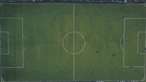 Flygfoto av gröna fotbollsplan och människor som spelar fotboll på vintern. Klipp. Hårda träningar under vintersäsongen — Stockfoto