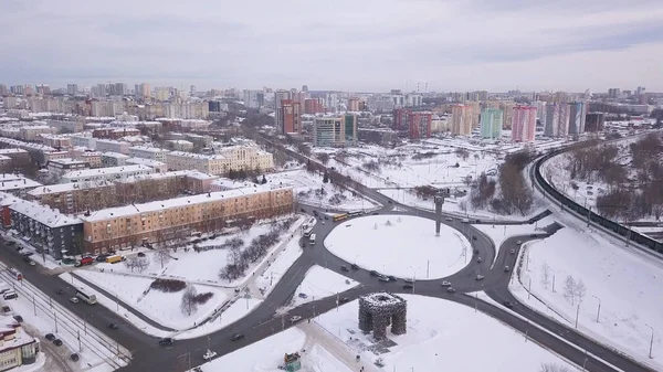Luchtfoto van de kruising van een cirkel met verkeer, oude en moderne gebouwen en wegen bedekt met sneeuw tegen de grijze lucht in de winter. Een knip. Stedelijk winterlandschap — Stockfoto